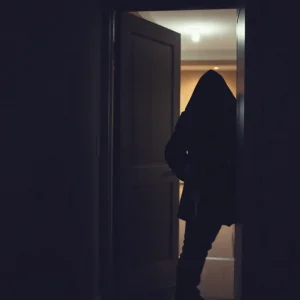 Silhouette of a burglar entering a hotel room with a master key
