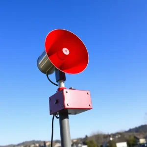 An outdoor warning siren against a blue sky