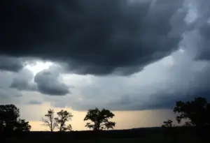 Dark storm clouds over a Kentucky landscape with windswept trees