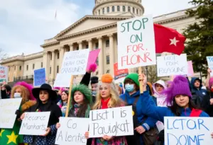 Protesters at the Kentucky State Capitol holding signs against Trump administration policies.